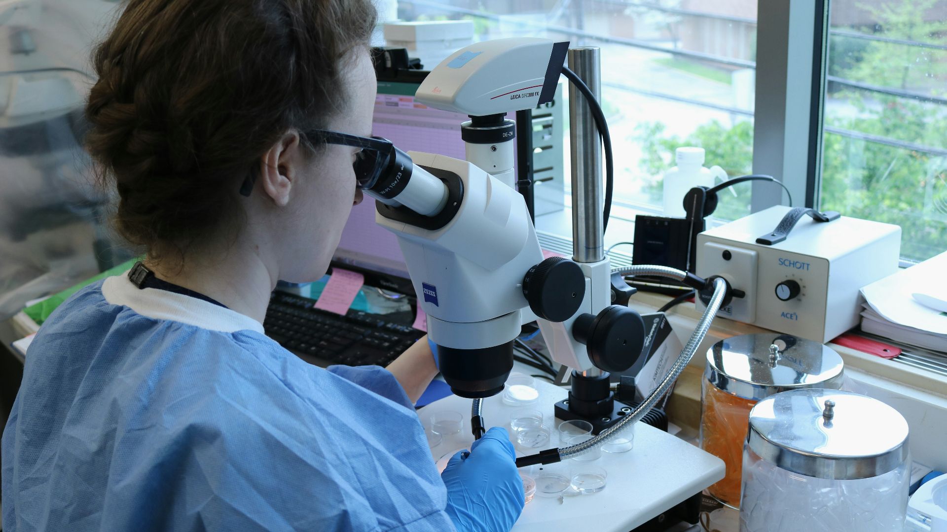a woman in a lab coat looking through a microscope