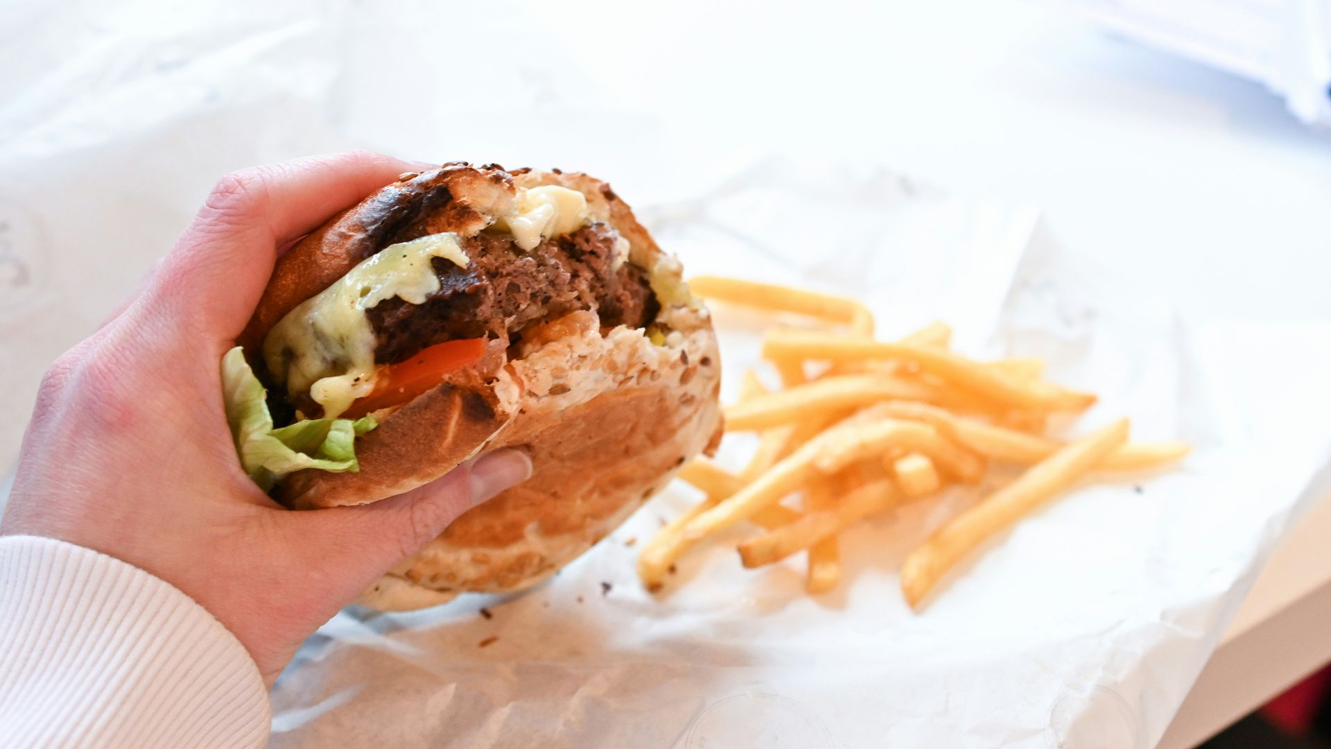 a person holding a sandwich and french fries