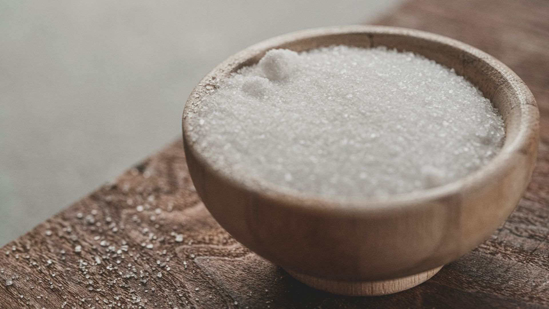 a wooden bowl filled with sugar on top of a wooden table