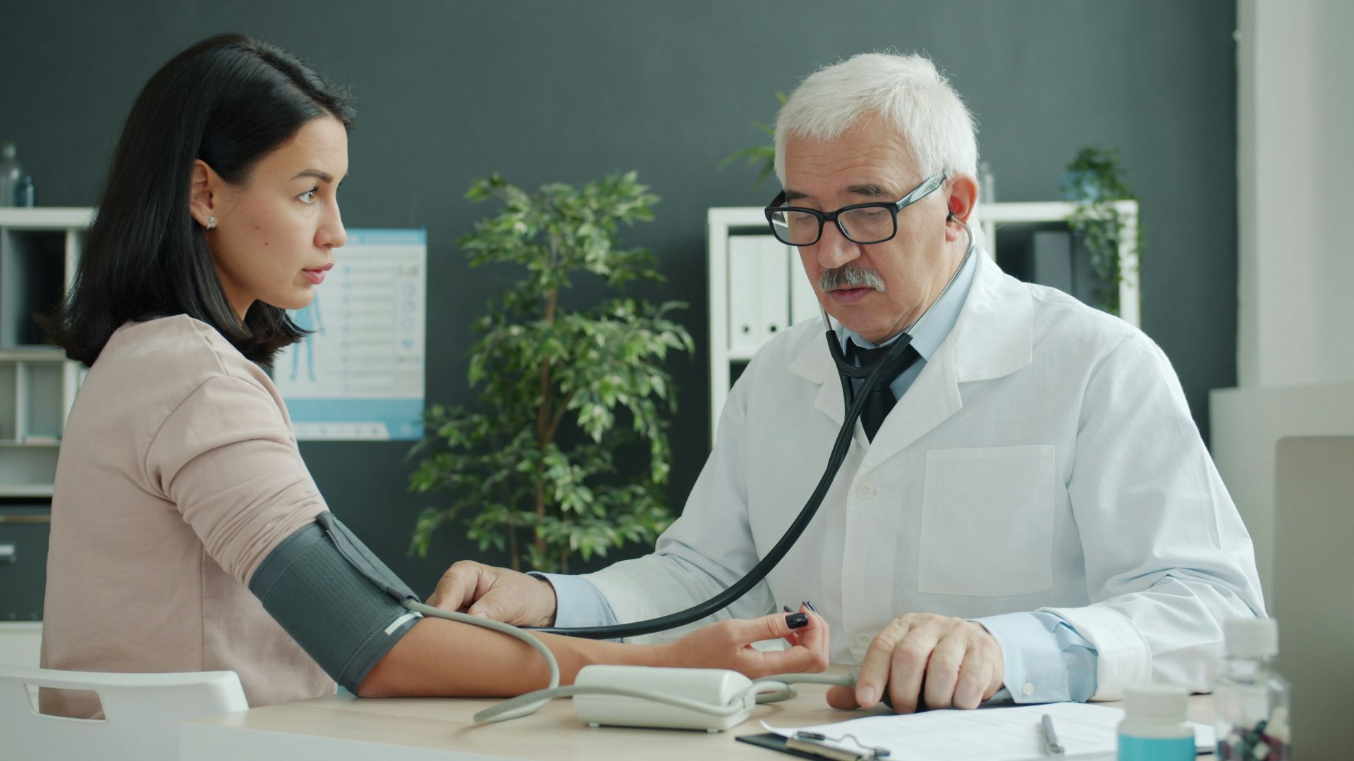 Doctor checks patient's blood pressure with stethoscope.