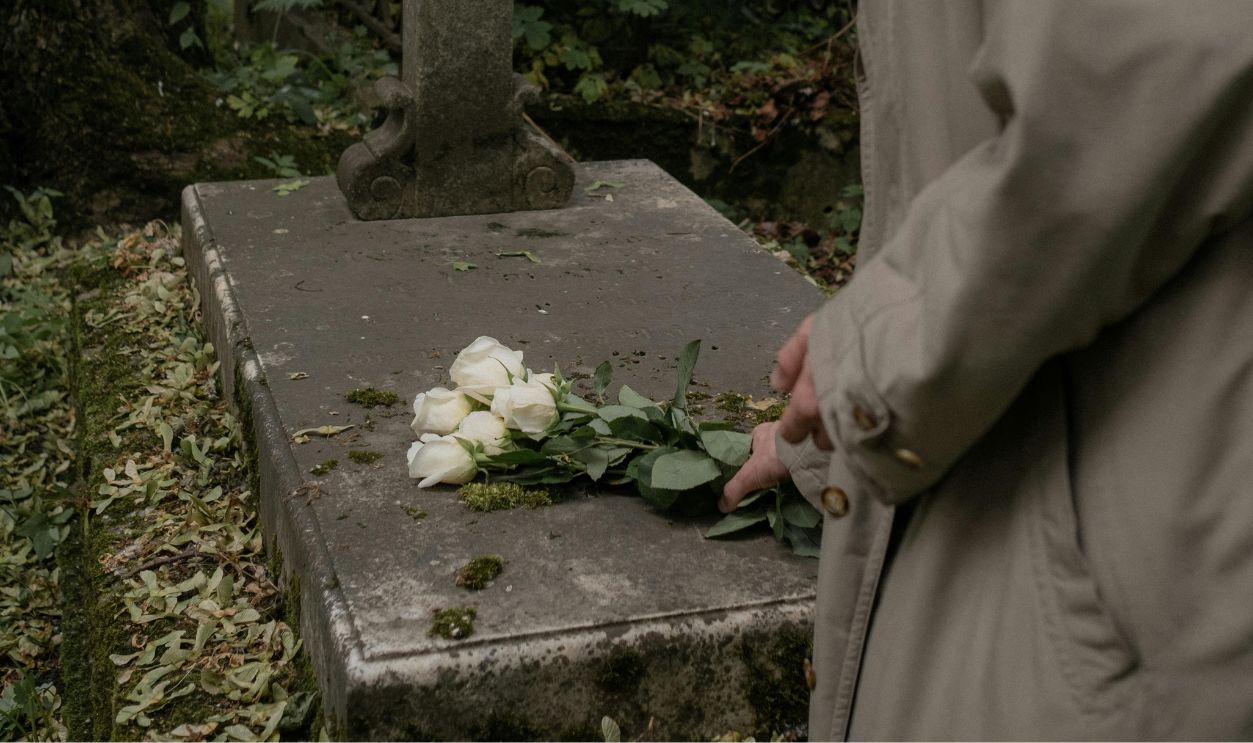 Man placing flowers on a grave