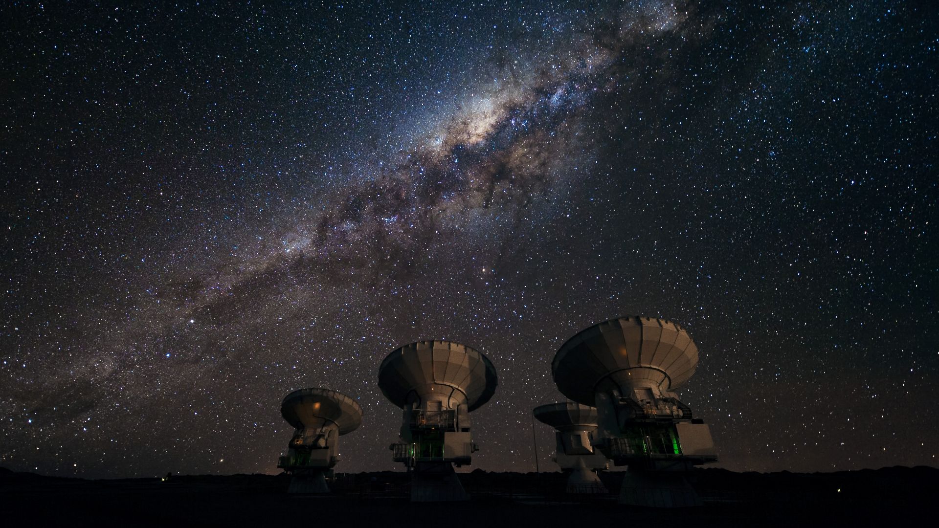 Four of the first ALMA antennas at the Array Operations Site (AOS), located at 5000 metres altitude on the Chajnantor plateau, in the II Region of Chile. Three of them — those which are pointing in the same direction — are being tested together as part of the ongoing Commissioning and Science Verification process. Across the image in the background is the impressive plane of the Milky Way, our own galaxy, here seen looking toward the centre. The centre of our galaxy is visible as a yellowish bulge crossed by dark lanes. The dark lanes are huge clouds of interstellar dust that lie in the disc of the galaxy. While opaque in visible light, they are transparent at longer wavelengths, such as the millimetre and submillimetre radiation detected by ALMA. ALMA, the Atacama Large Millimeter/submillimeter Array, is the largest astronomical project in existence and is a truly global partnership between the scientific communities of East Asia, Europe and North America with Chile. ESO is the European partner in ALMA.