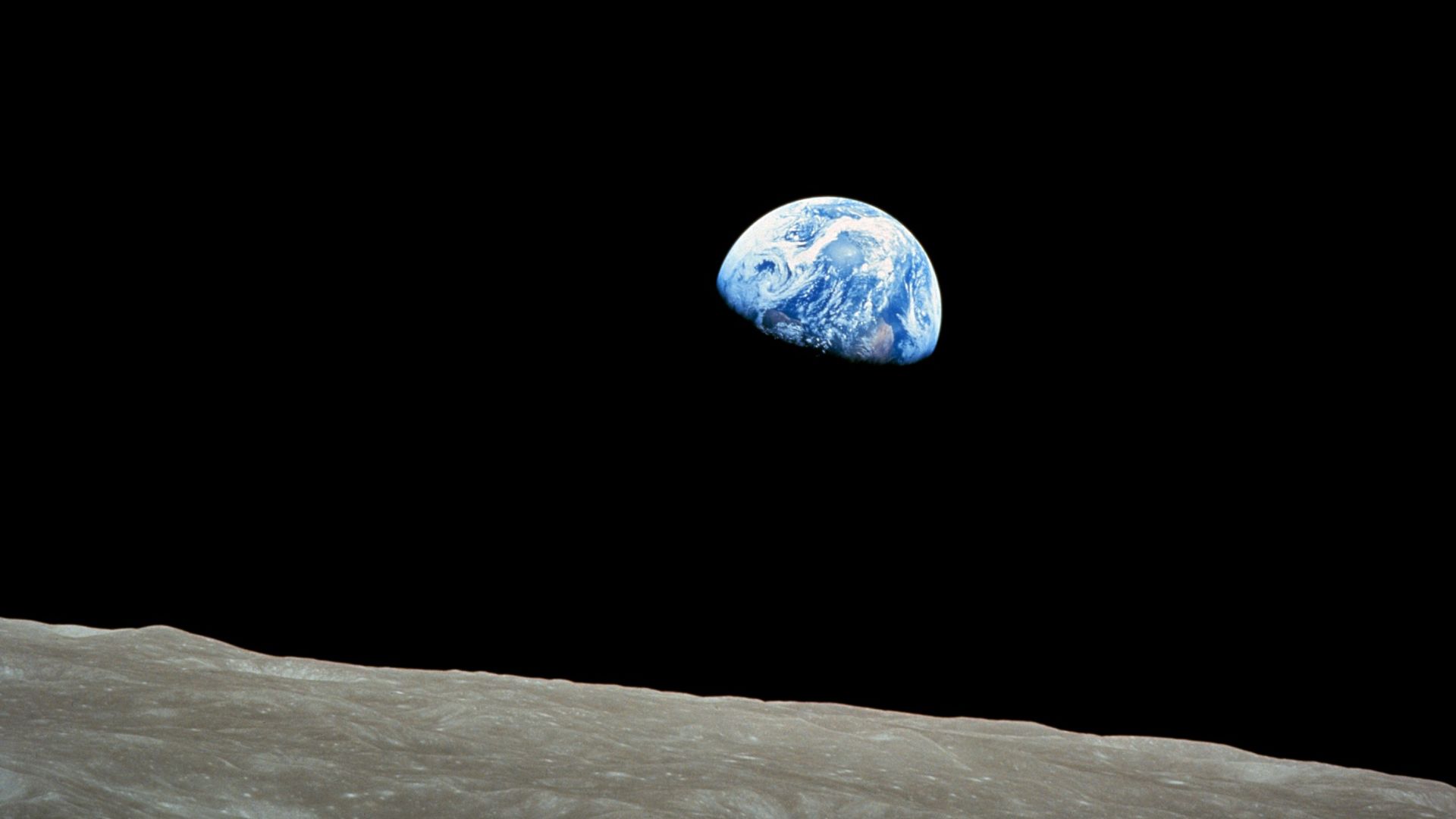 Taken by Apollo 8 crewmember Bill Anders on December 24, 1968, at mission time 075:49:07 [8] (16:40 UTC), while in orbit around the Moon, showing the Earth rising for the third time above the lunar horizon. The lunar horizon is approximately 780 kilometers from the spacecraft. Width of the photographed area at the lunar horizon is about 175 kilometers. [9] The land mass visible just above the terminator line is west Africa. Note that this phenomenon is only visible to an observer in motion relative to the lunar surface. Because of the Moon's synchronous rotation relative to the Earth (i.e., the same side of the Moon is always facing Earth), the Earth appears to be stationary (measured in anything less than a geological timescale) in the lunar