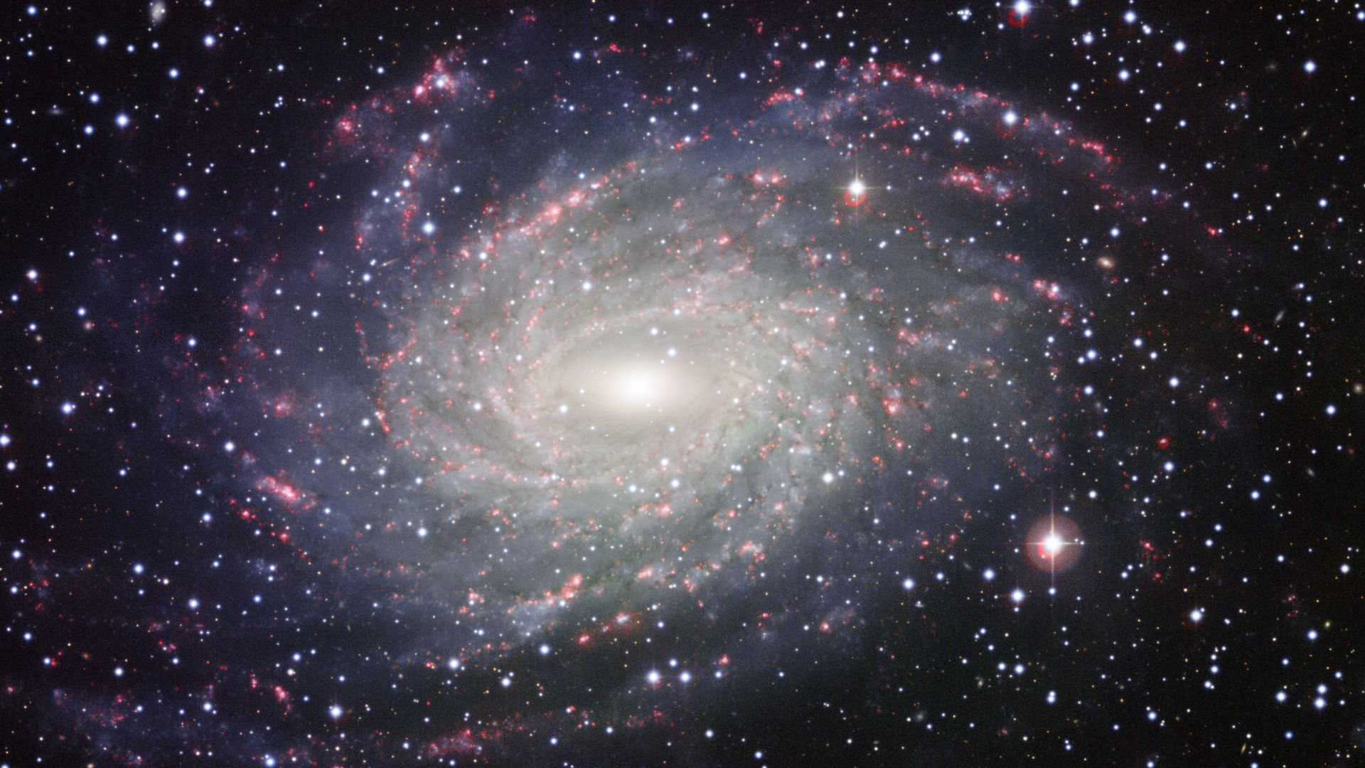 This picture of the nearby galaxy NGC 6744 was taken with the Wide Field Imager on the MPG/ESO 2.2-metre telescope at La Silla. The large spiral galaxy is similar to the Milky Way, making this image look like a picture postcard of our own galaxy sent from extragalactic space. The picture was created from exposures taken through four different filters that passed blue, yellow-green, red light, and the glow coming from hydrogen gas. These are shown in this picture as blue, green, orange and red, respectively.