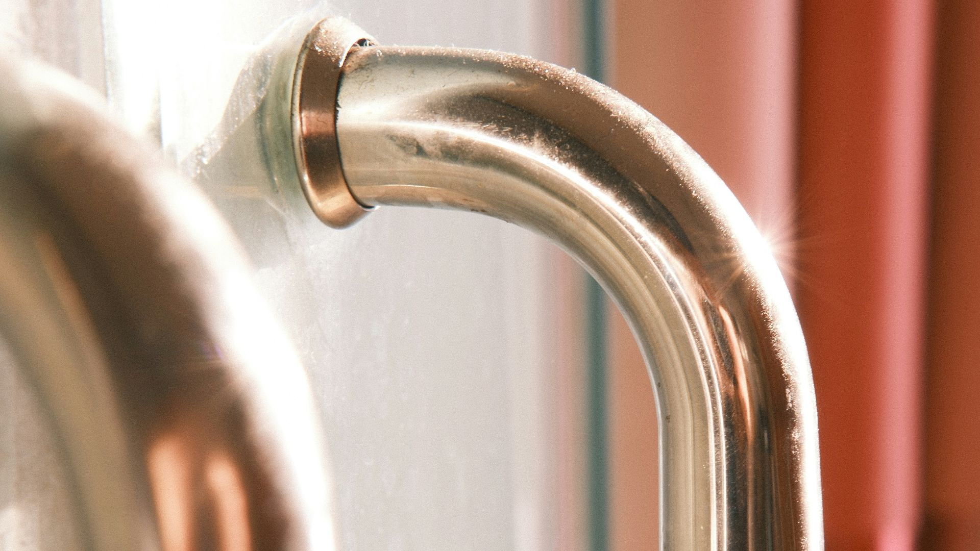 Close-up of a shiny metal door handle with curtains