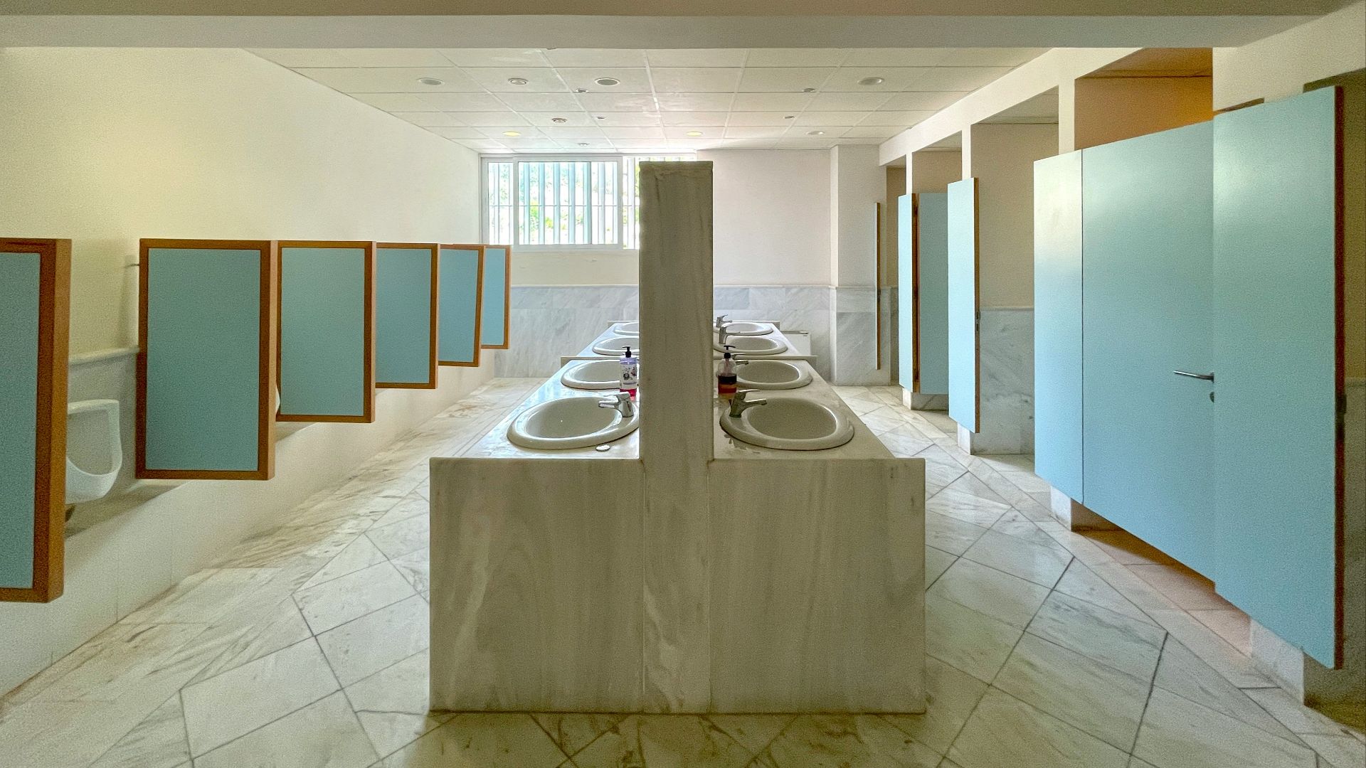 Row of sinks and stalls in a public restroom.