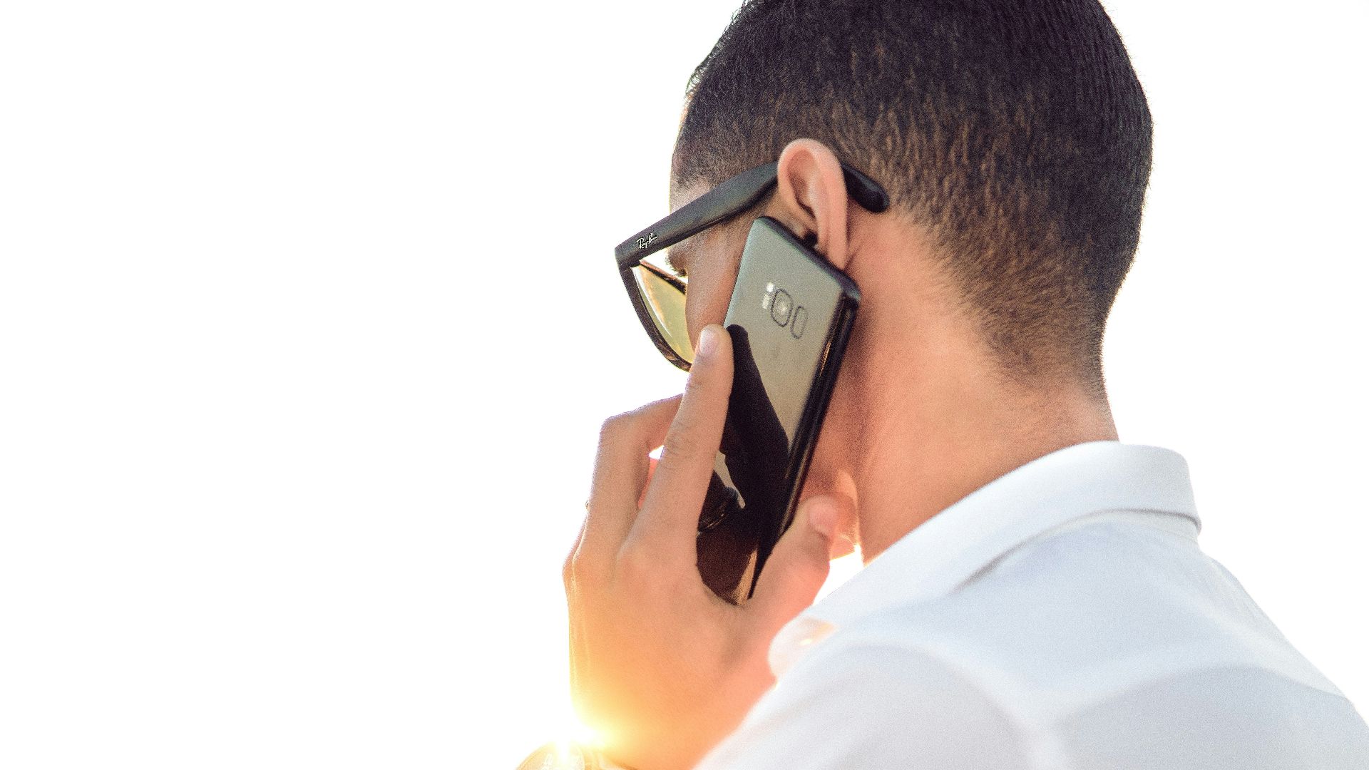 man holding smartphone standing in front of calm body of water