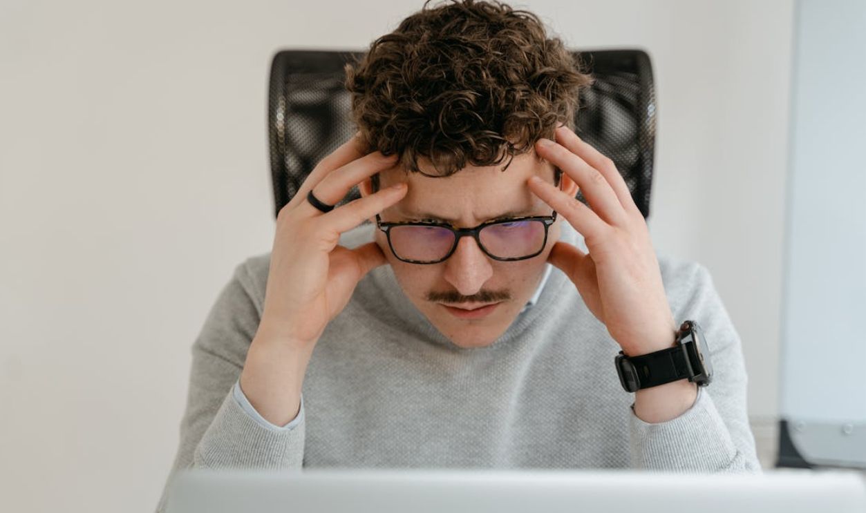 Man in Gray Sweater Holding His Head with Hands