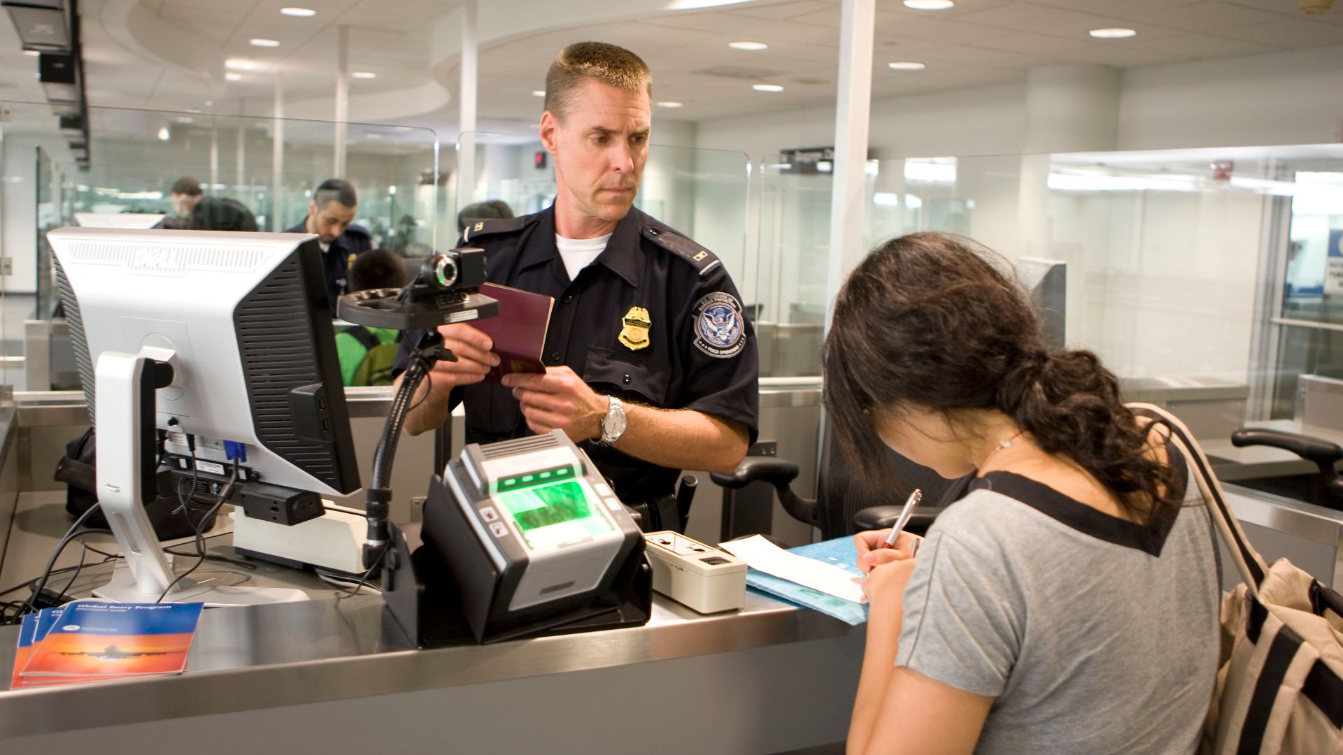 CBP Officer processes a passenger into the United States at an airport. Photo by James Tourtellotte