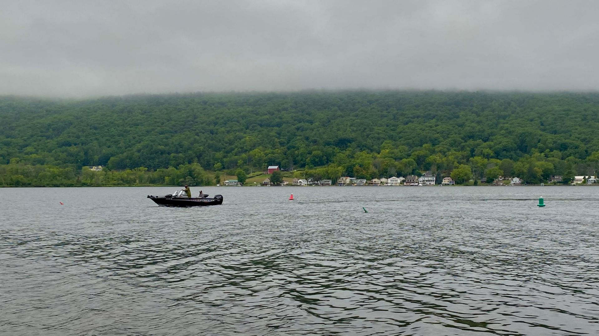 A fisherman on a speedboat cruises Honeoye Lake on a murky September 2022 afternoon, as seen from the boat launch at the State Marine Park on East Lake Road in the town of Richmond, New York.