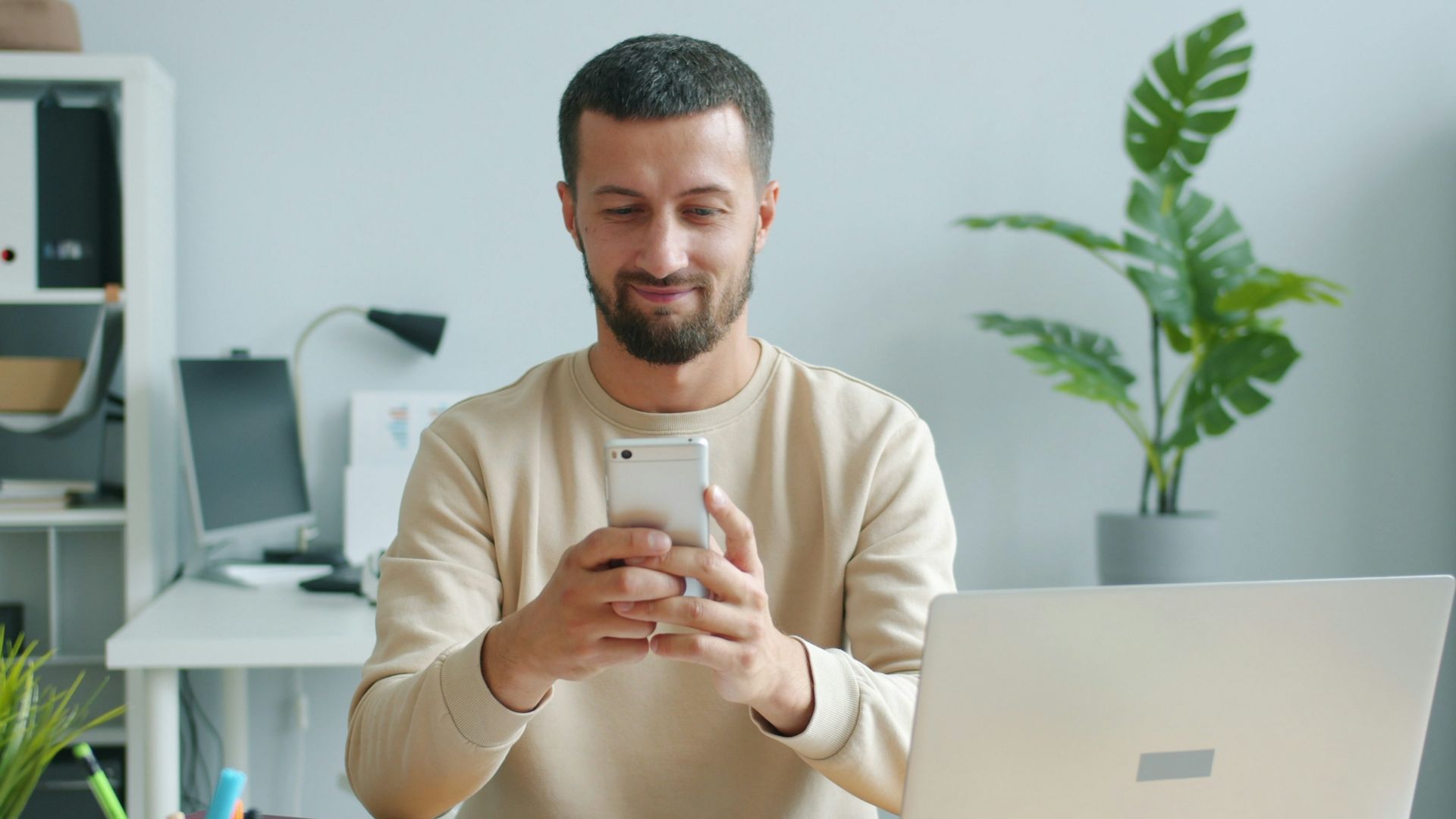 Man smiling while looking at his smartphone at his phone.