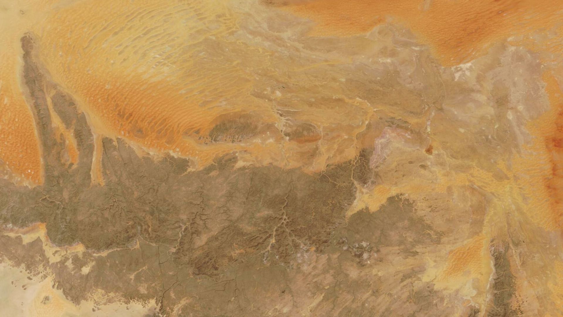 In south-eastern Algeria, sitting at the borders of Libya, Niger, and Mali, a vast and ancient plateau rises from the Sahara Desert. On October 9, 2022, the Moderate Resolution Imaging Spectroradiometer (MODIS) on board NASA’s Terra satellite acquired a true-color image of this rugged region of rock and orange sand dunes, which is known as Tassili n’Ajjer.
The name Tassili n’Ajjer translates to “plateau of chasms,” which clearly describes the deep fissures and canyons long ago cut into the rock by flowing water. The dune field, seen in this image as orange roughly parallel lines, took shape after an ancient lake dried up. The dark area is predominately formed of sandstone.

Tassili n’Ajjer is a UNESCO World Heritage Site with more than 15,000 prehistoric etchings and illustrations on the cave walls; these record a human presence as far back as 6000 BCE.