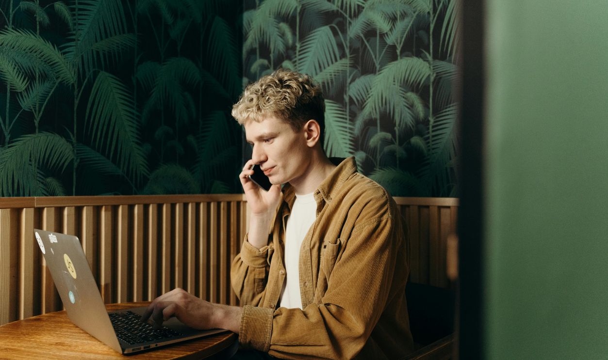 Man in Talking on the Phone While Using a Laptop