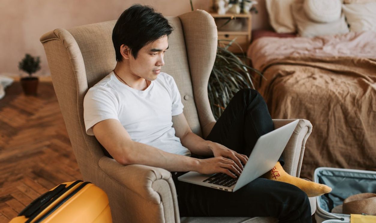 Man Sitting in an Armchair and Using Laptop
