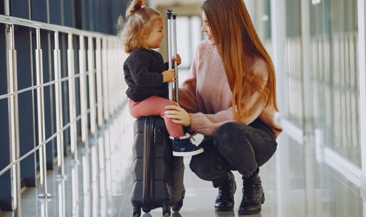 Smiling mother with daughter and suitcase in airport