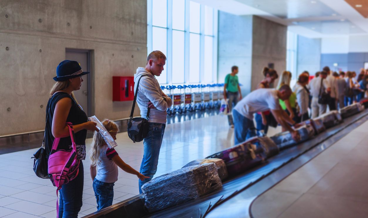 Family waiting their suitcase on baggage carousel in airport terminal