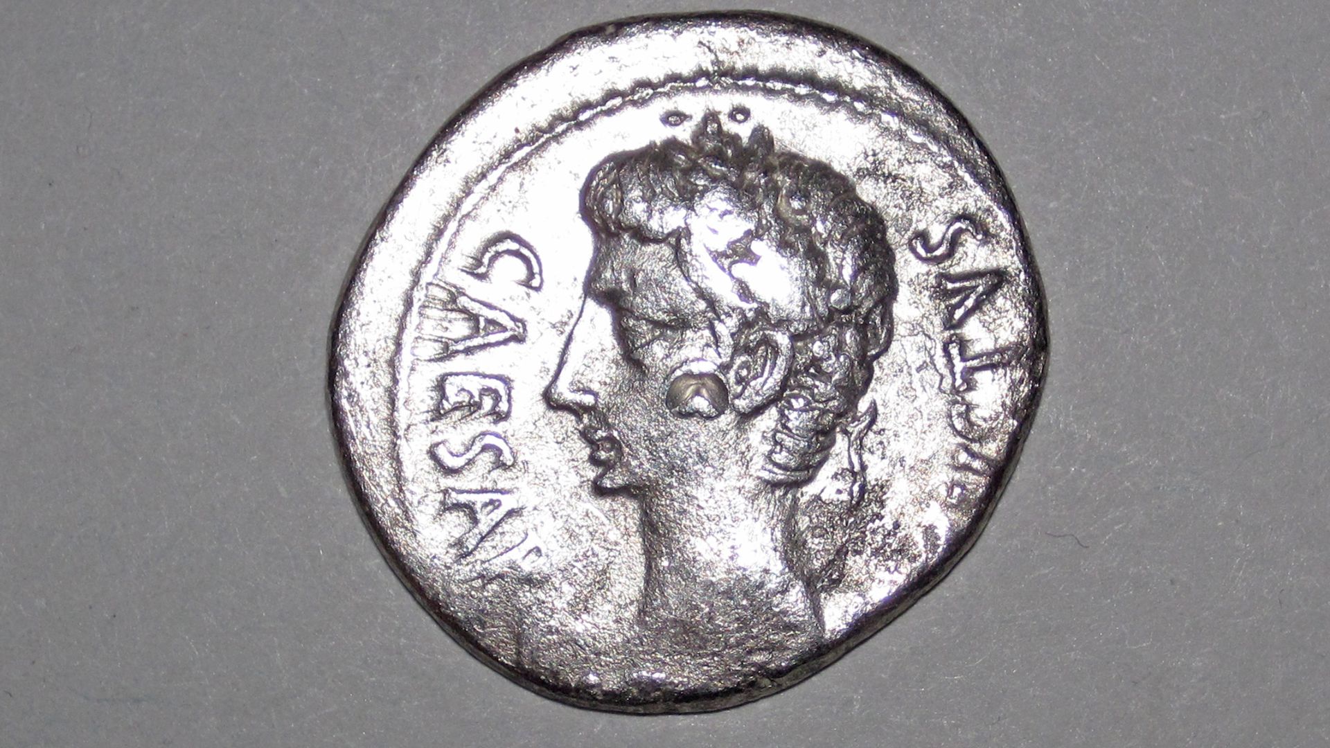 This is a ~2040 year old, one denarius silver coin issued by the Roman Empire.  The portrait depicts Caesar Augustus (real name: Gaius Octavian), the first emperor of the ancient Roman Empire - he ruled from 27 B.C. to 14 A.D.
This coin was produced at the Caesaraugusta Mint in Spain (= modern day city of Zaragoza) in 19 to 18 B.C.  The flip side depicts a comet that appeared in the year 44 B.C.  The pit on the cheek is a