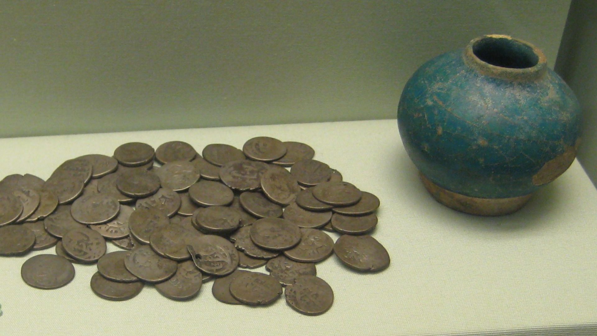 Pot hoard comprising 78 Persian silver coins in a small blue-glazed pot, from Sharjah in Trucial Oman, late 17th century.