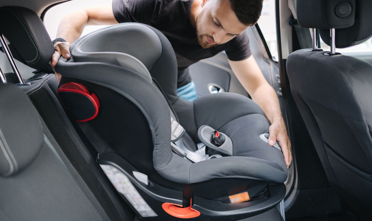 Shutterstock-2421751705, Man installs a child car seat in car