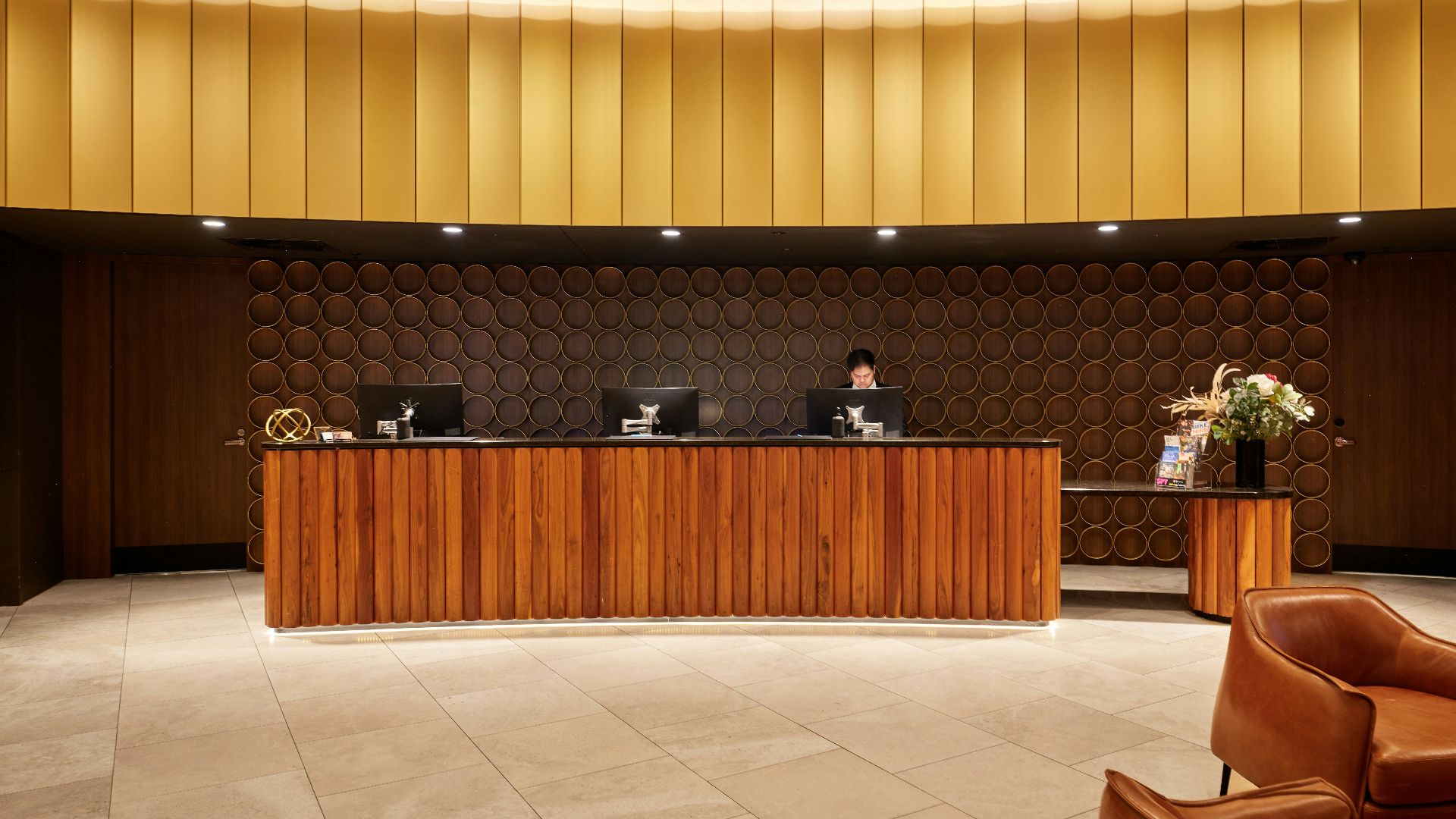Hotel reception desk with modern wooden furniture and seating.