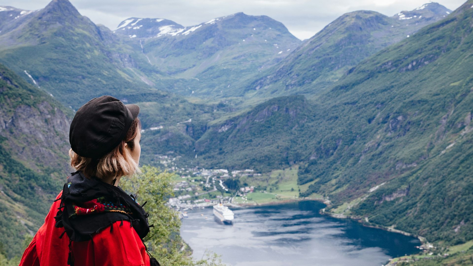 a woman standing on top of a lush green hillside