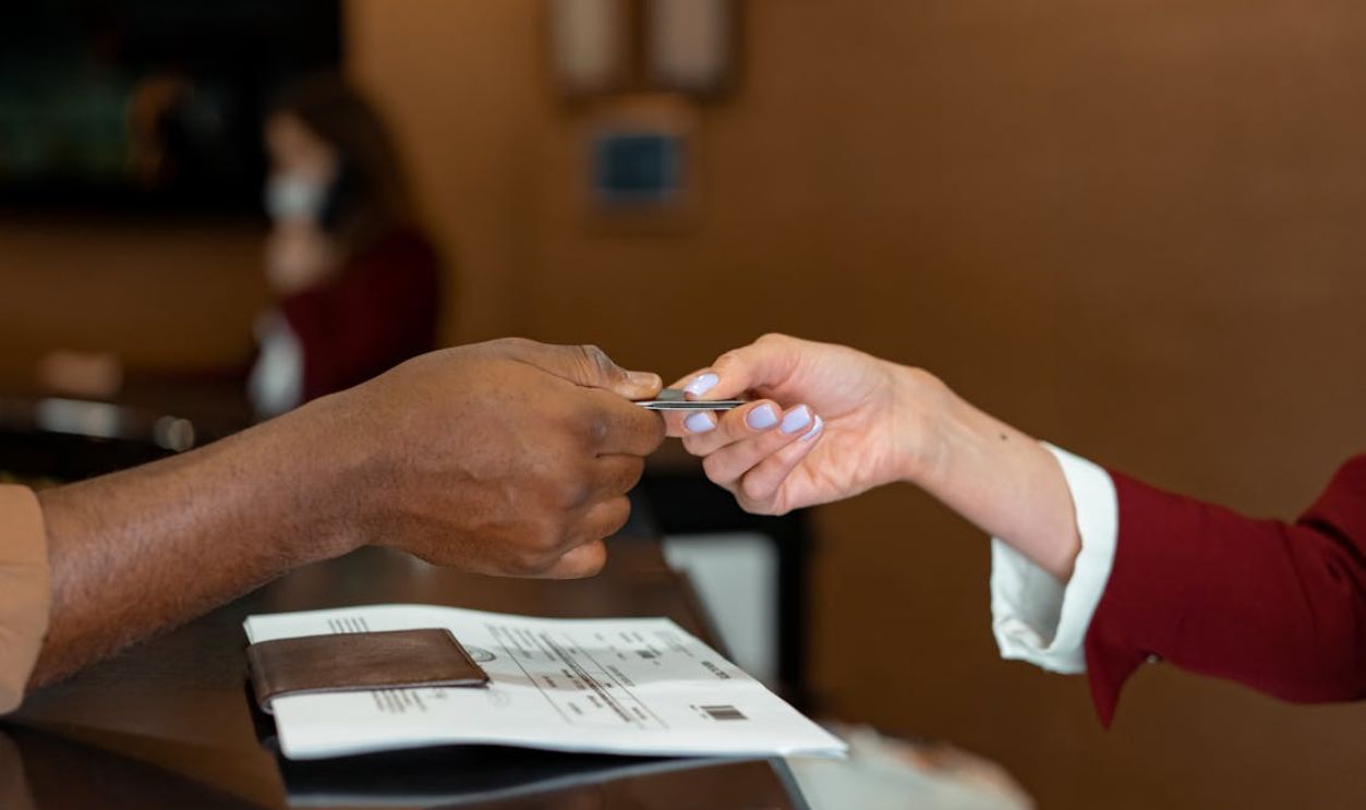 Man Handing a Credit Card to a Hotel Receptionist