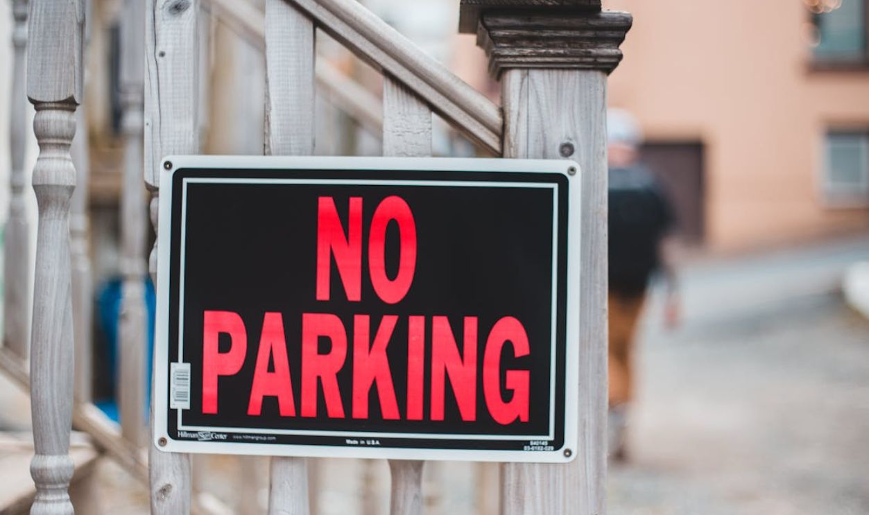 A No Parking Sign on a Wooden Hand Rail