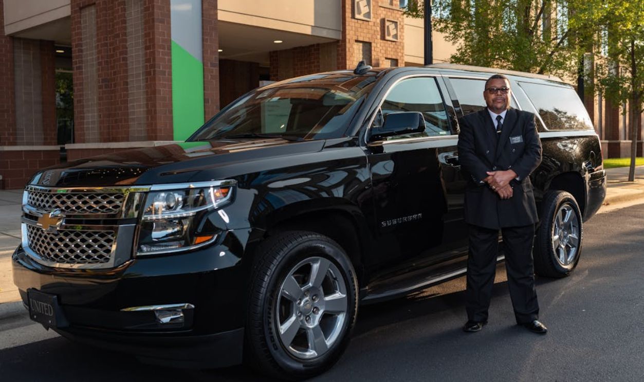 Chauffeur Standing by Luxury Black SUV Outdoors