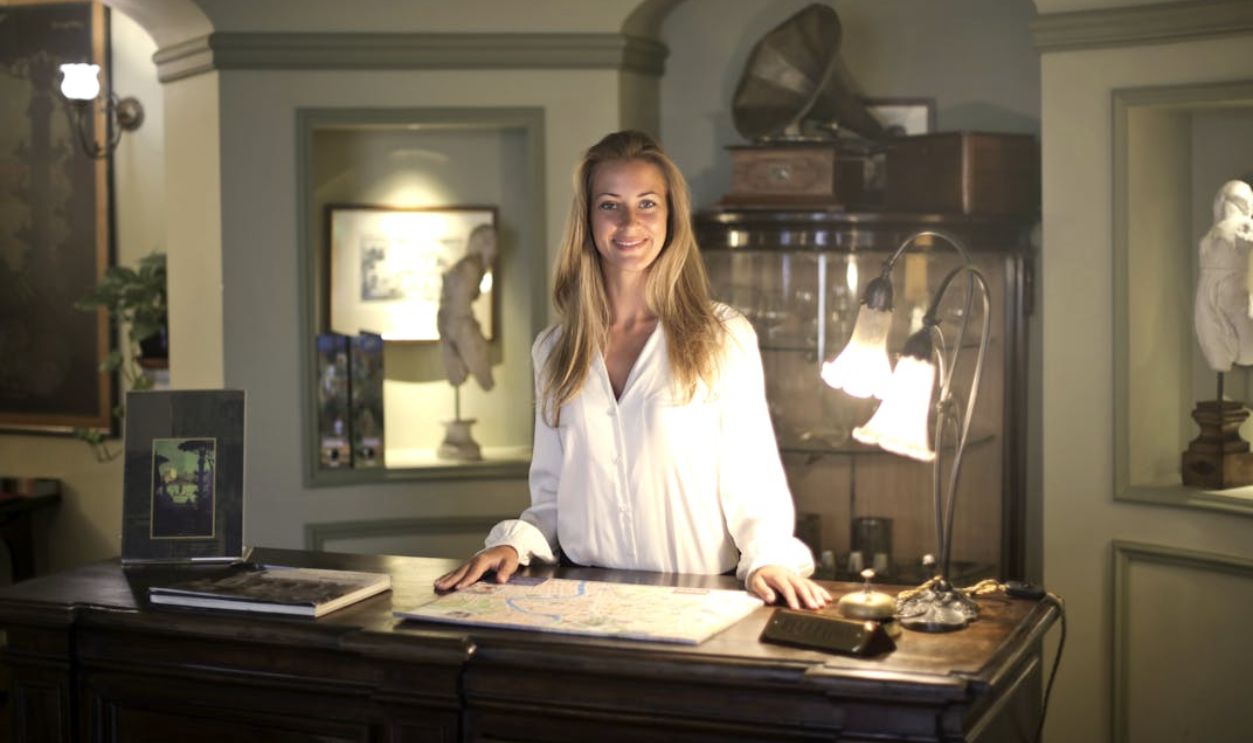 Hospitable Woman Standing Behind Front Desk