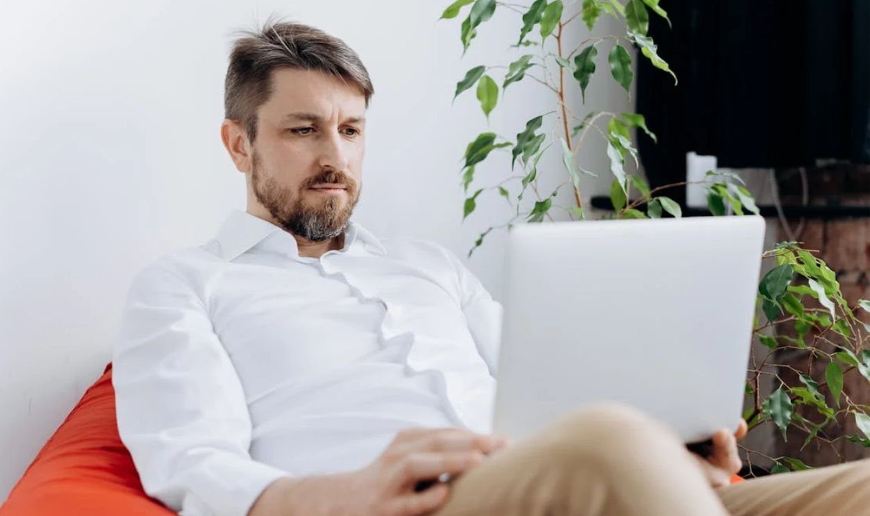 A Man in White Long Sleeves Using a Laptop