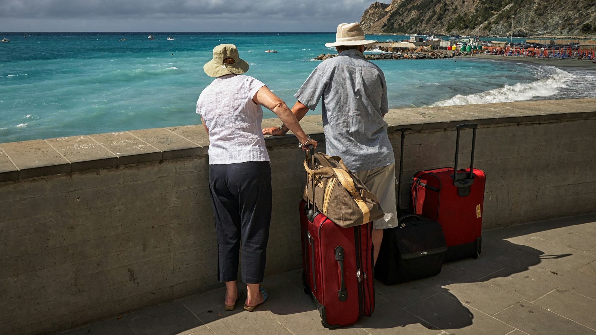 man and woman standing beside concrete seawall looking at beach