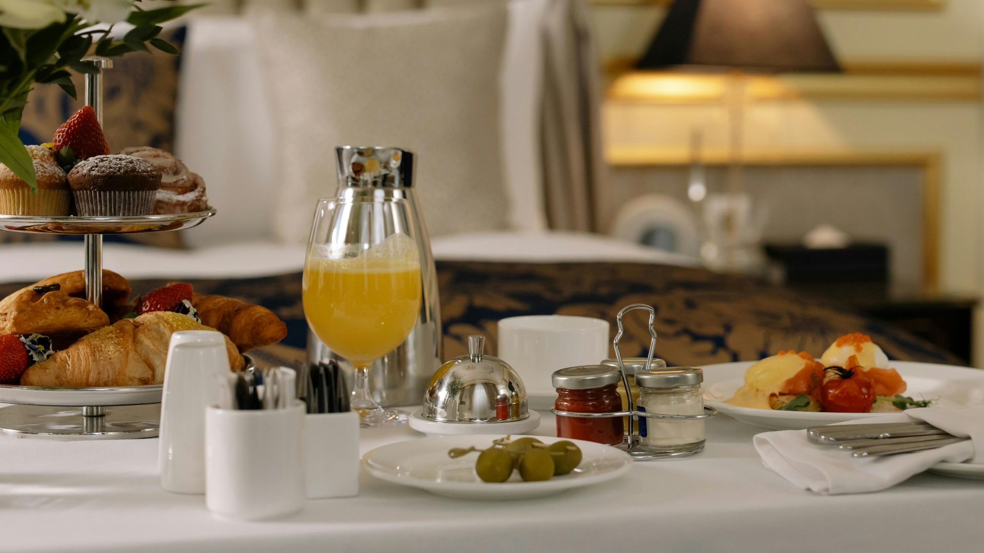 Elegant hotel room breakfast featuring pastries, orange juice, and a stylish table setting.
