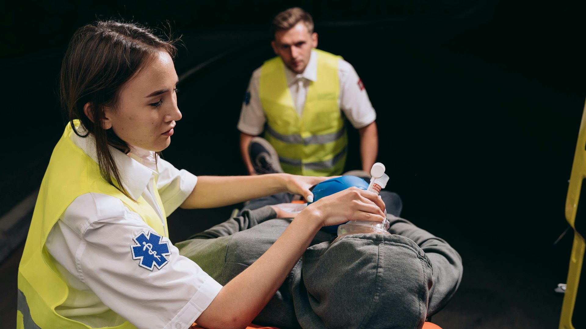 Paramedics provide critical care to a patient during a nighttime emergency response.
