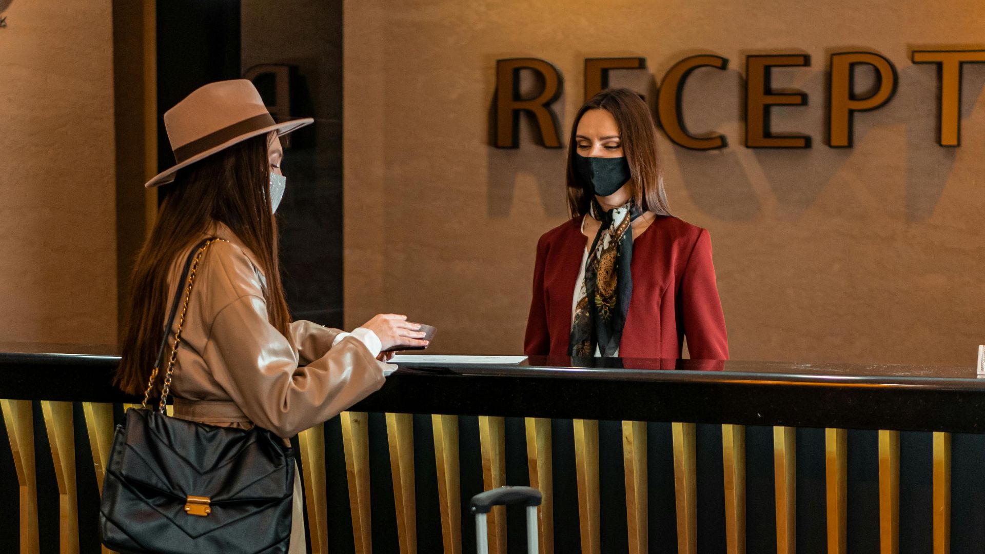 Businesswoman checking into a hotel at a stylish reception desk, engaging with staff.
