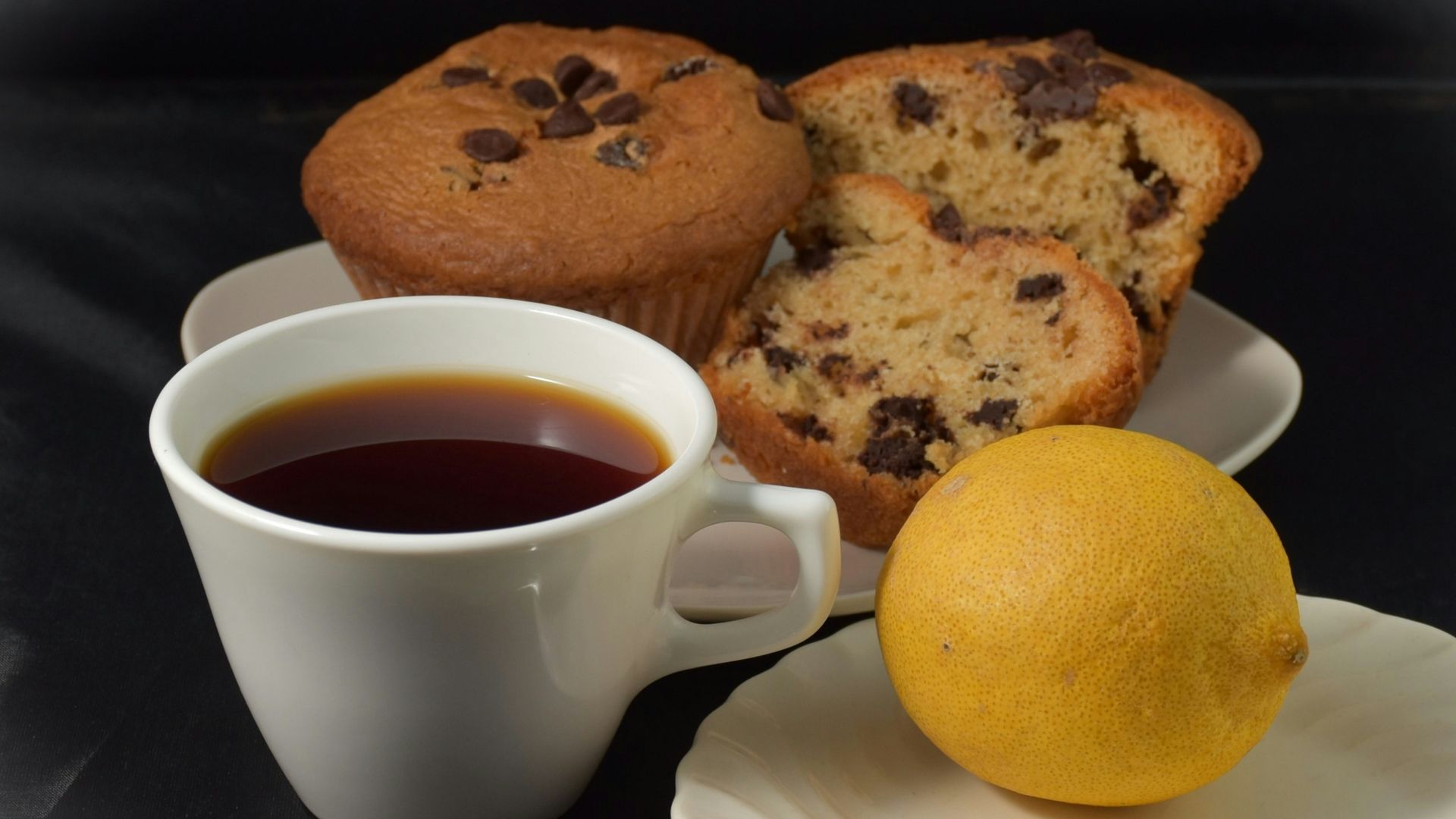 Cup of coffee with chocolate chip muffins and lemon