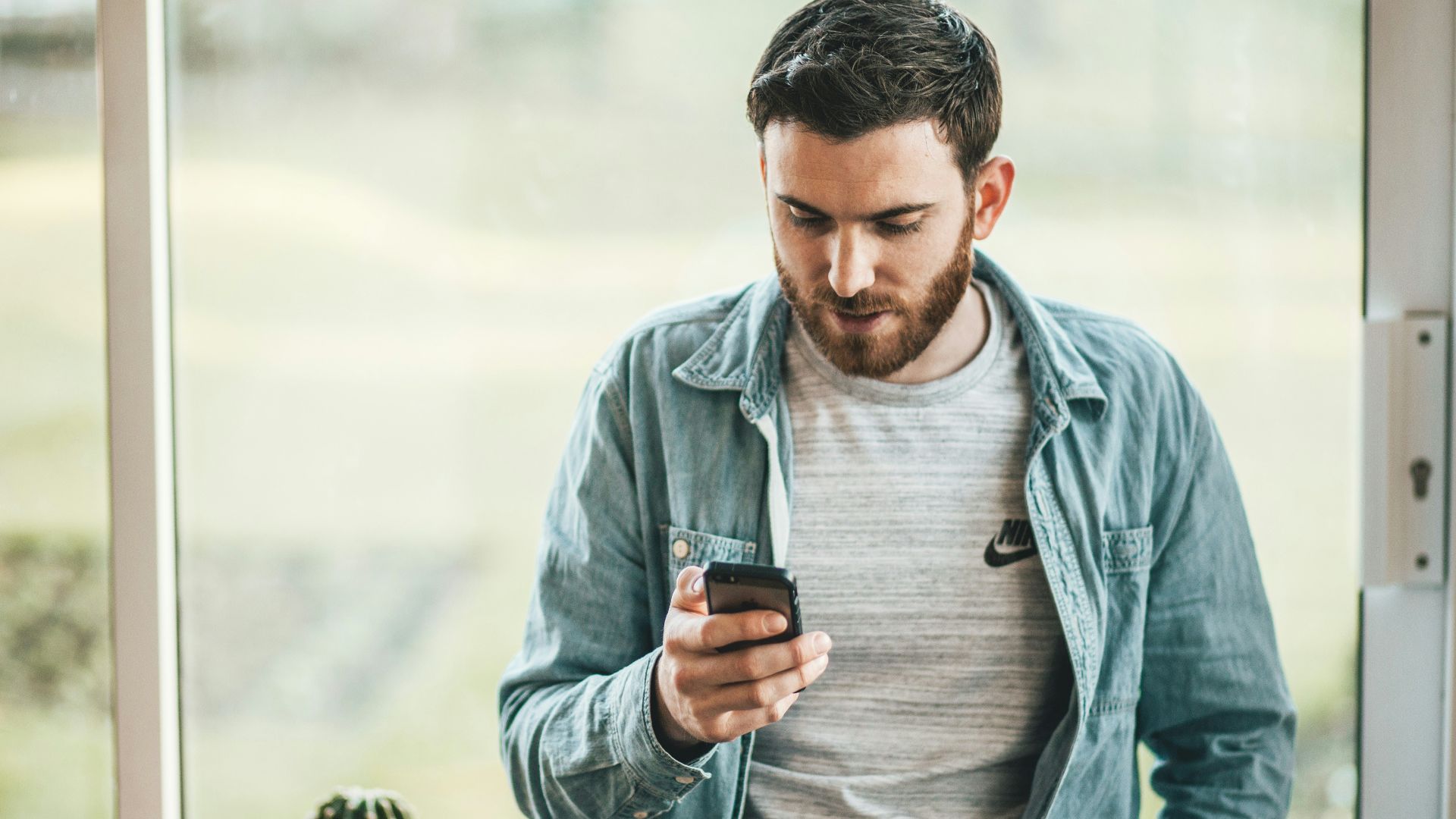 man holding a smartphone near the window