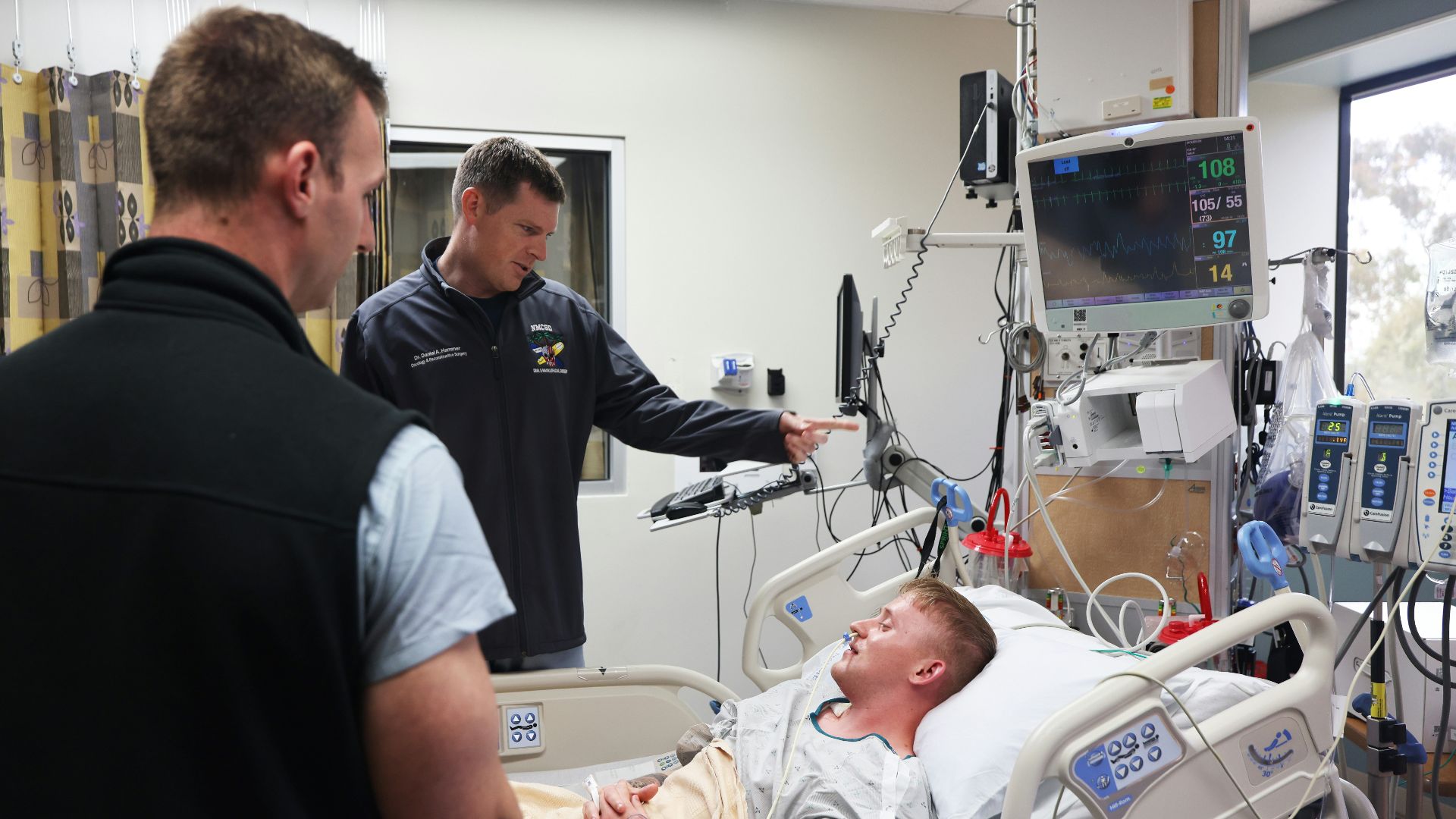 Doctors discuss patient's condition near hospital bed.