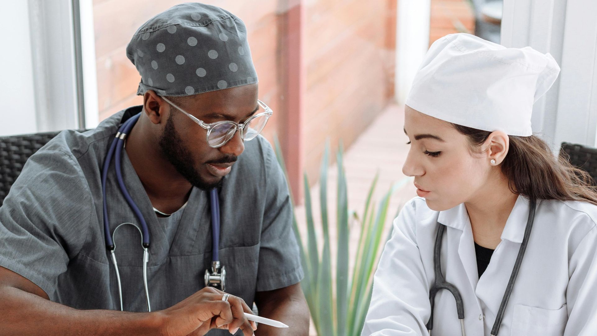 Two doctors discussing patient care with devices on a glass table indoors.