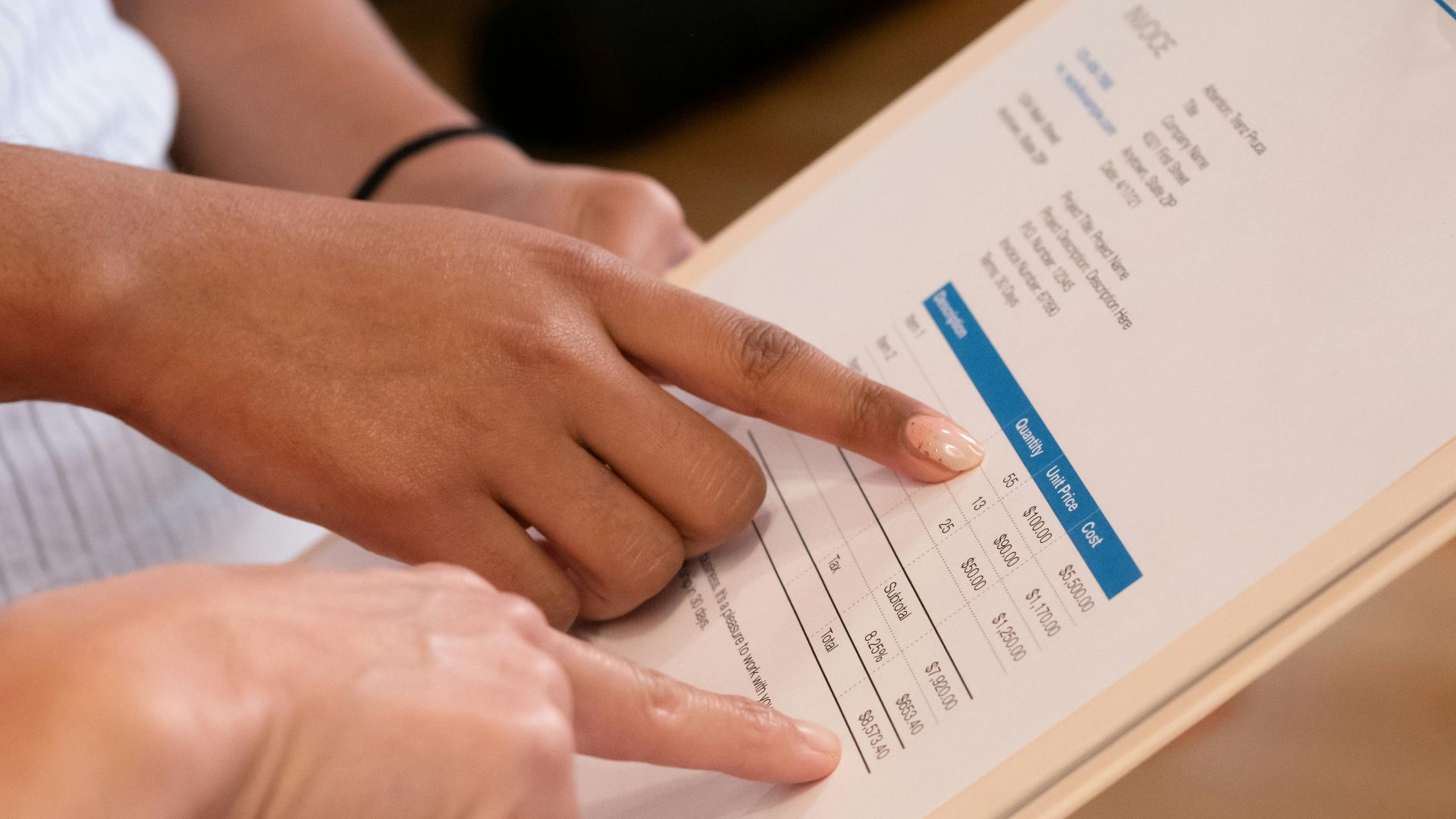 Two people pointing at financial details on a document, highlighting invoice analysis.