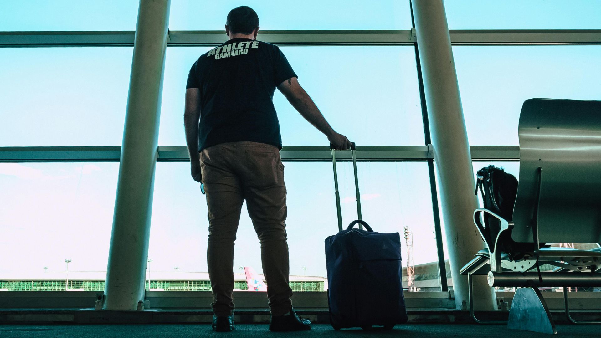 Man with luggage waiting at airport lounge, anticipating departure in a modern setting.