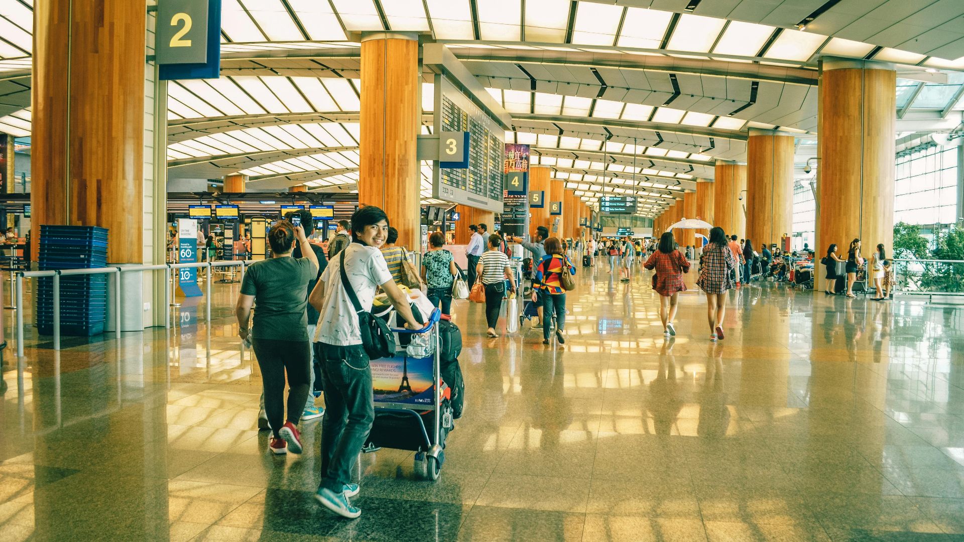 Travelers bustling through Singapore Changi Airport terminal, highlighting the dynamic and vibrant atmosphere of international travel.