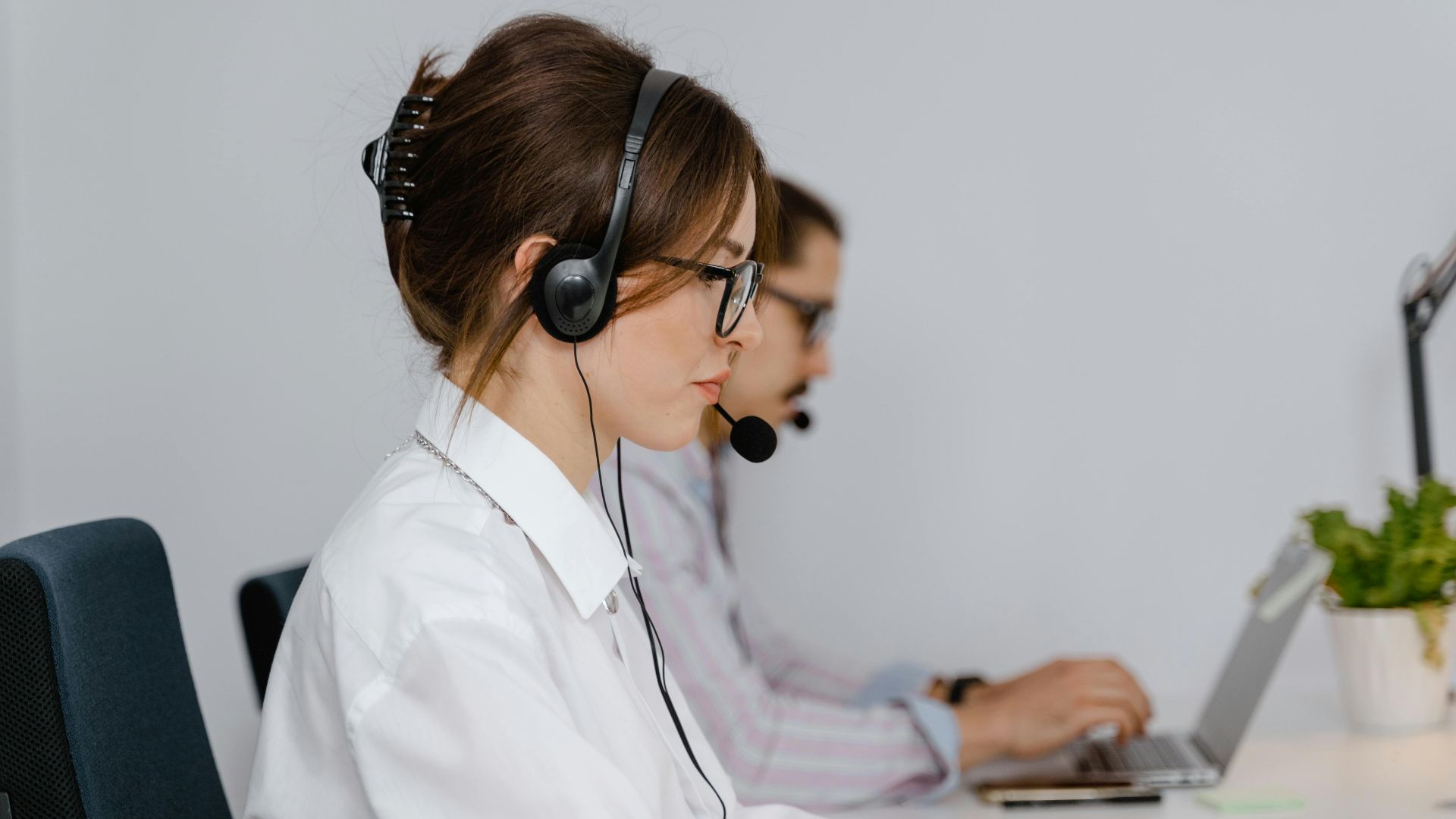 Customer service agents working at call center with headsets, focused on providing support.
