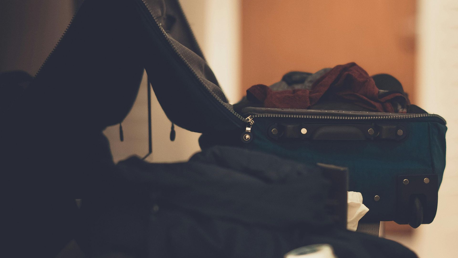 A warm-toned indoor image of an open suitcase with clothes, conveying travel readiness.