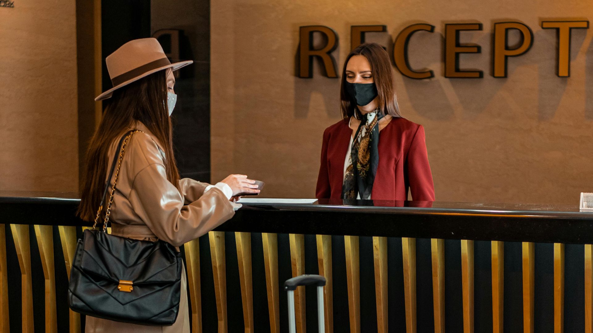 Businesswoman checking into a hotel at a stylish reception desk, engaging with staff.