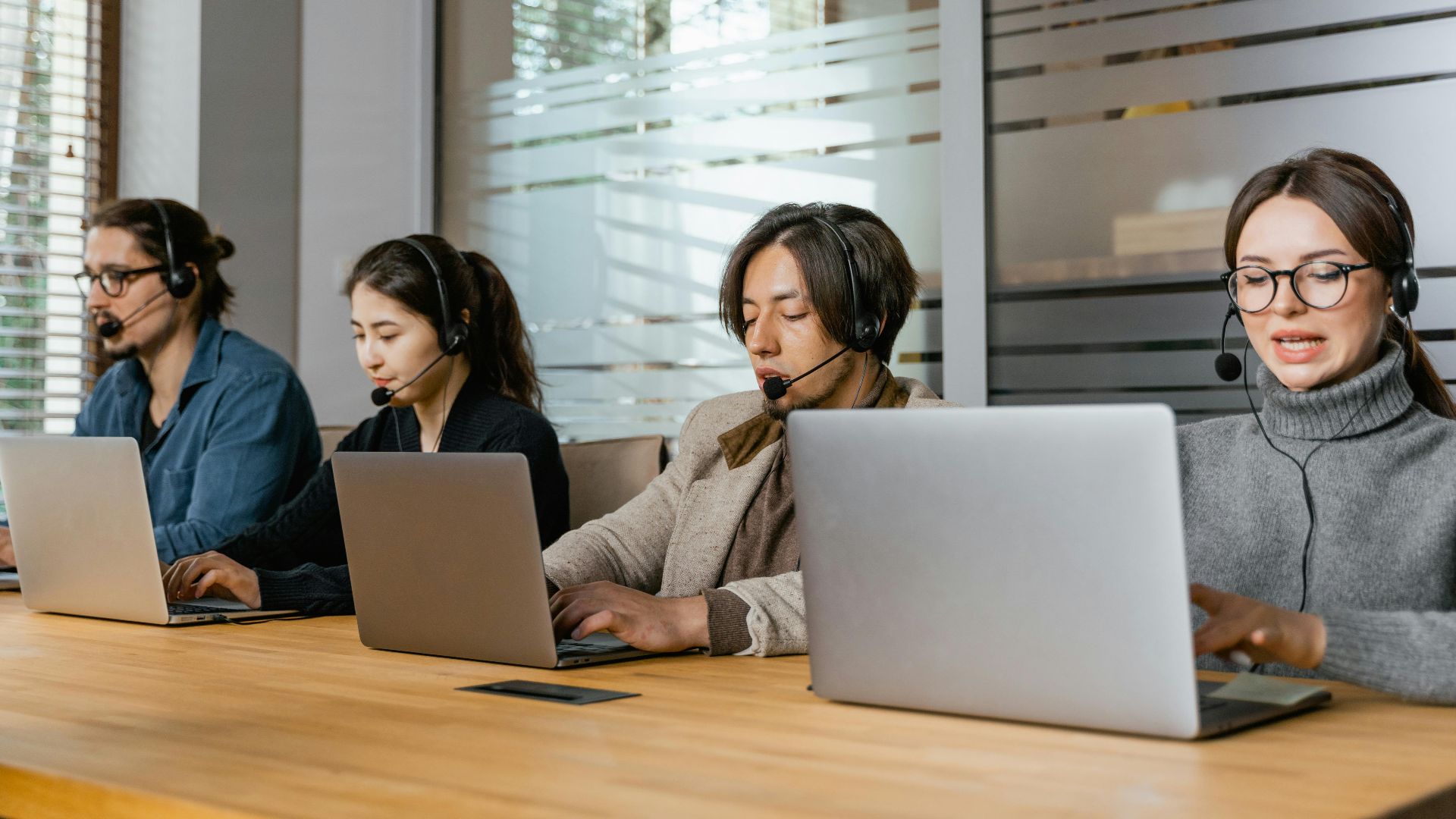 Four customer support agents working diligently in an office setting.