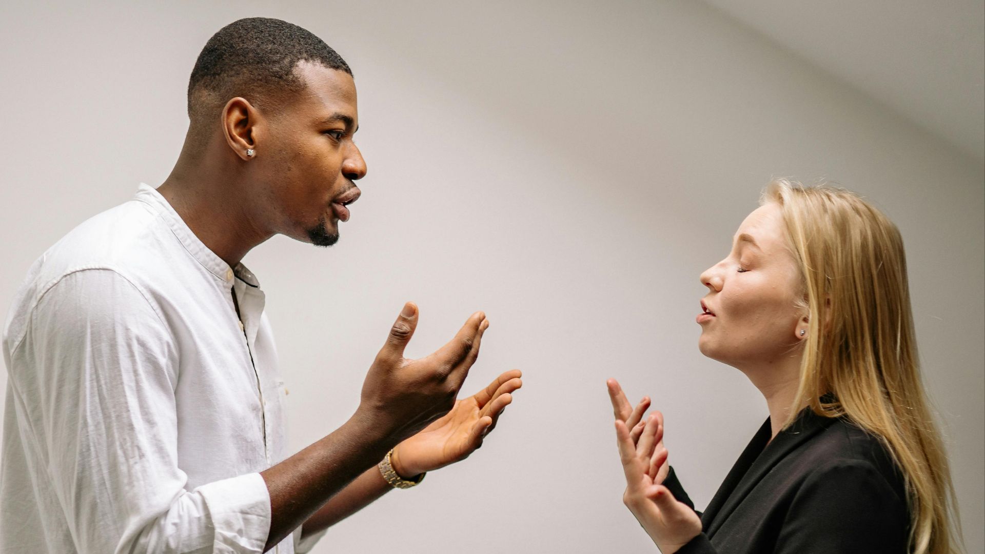 A couple engaged in a heated argument indoors, expressing strong emotions and gestures.