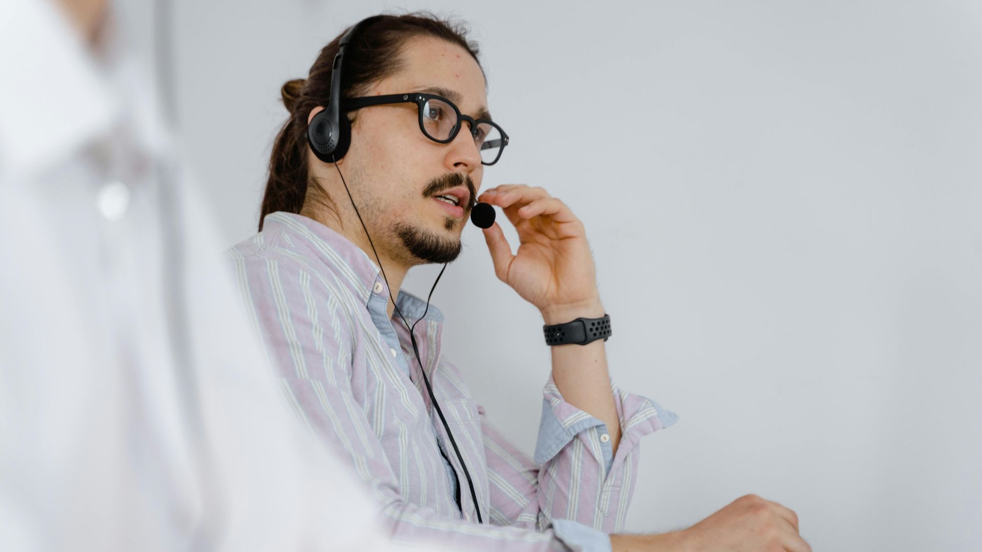 Focused customer service agent speaking on a headset in a modern office environment.