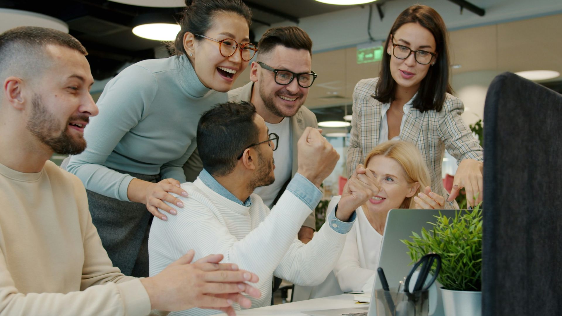 Diverse team celebrating success at office desk.