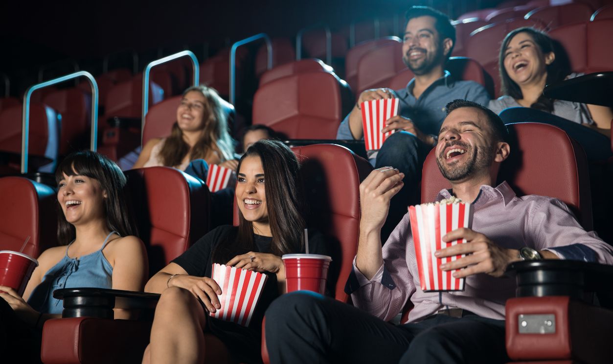 Small audience of people laughing at the movie theater while watching a comedy and having a good time.