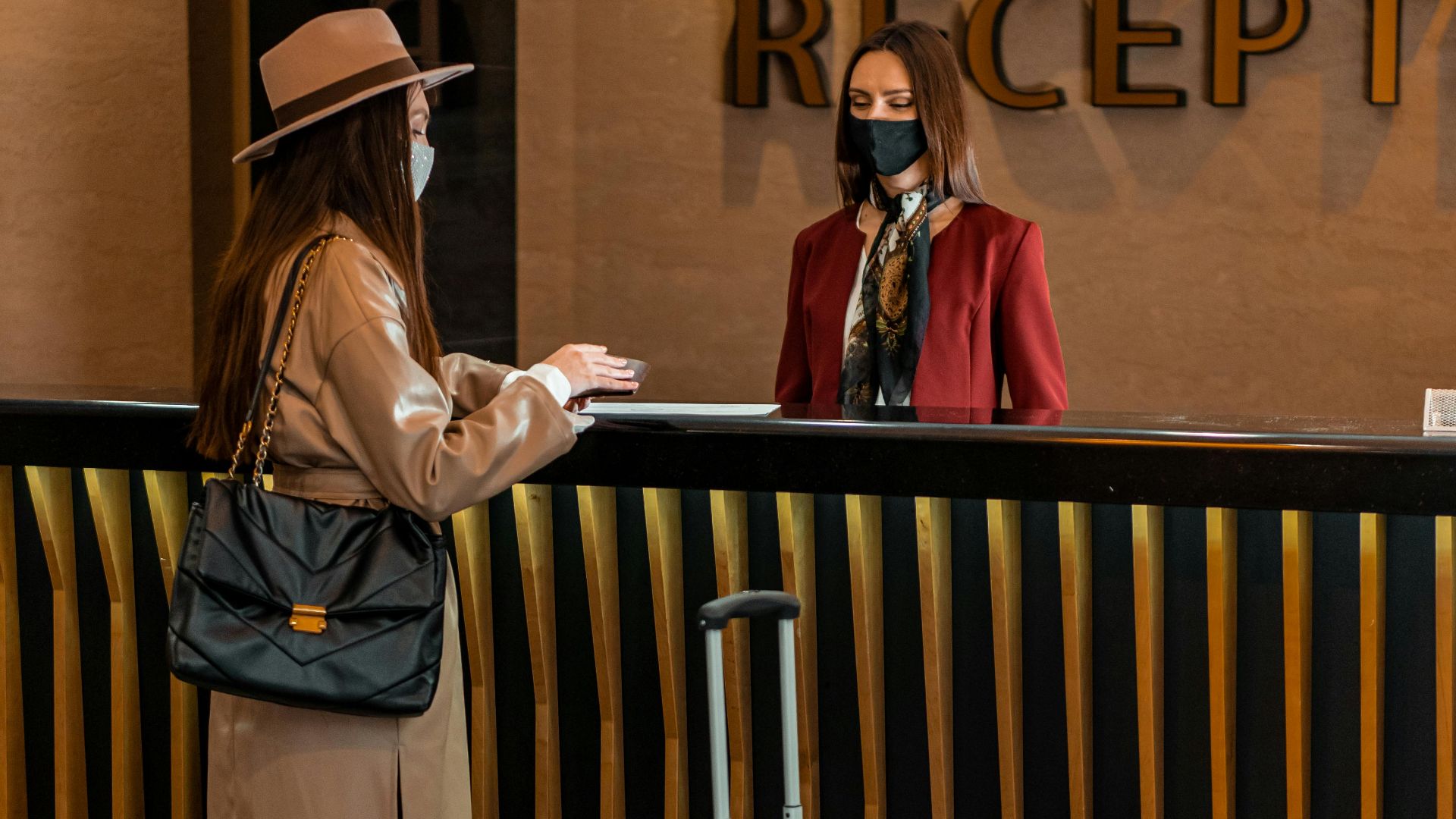 Businesswoman checking into a hotel at a stylish reception desk, engaging with staff.